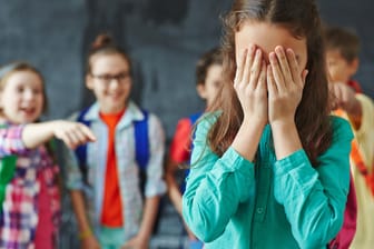 Kinder machen sich über Mitschülerin lustig: Mobbing ist eine Form der psychischen Gewalt.