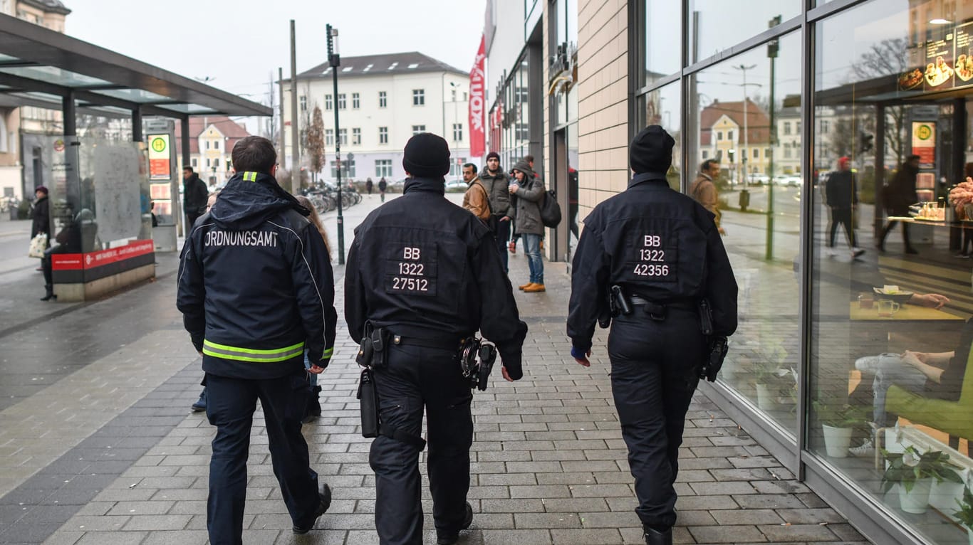 Ein Mitarbeiter des Ordnungsamtes und zwei Beamte der Bereitschaftspolizei gehen Streife vor einem Einkaufszentrum in Cottbus: Die Stadt wurde zum Schauplatz von hässlichen Angriffen zwischen Deutschen und Ausländern.