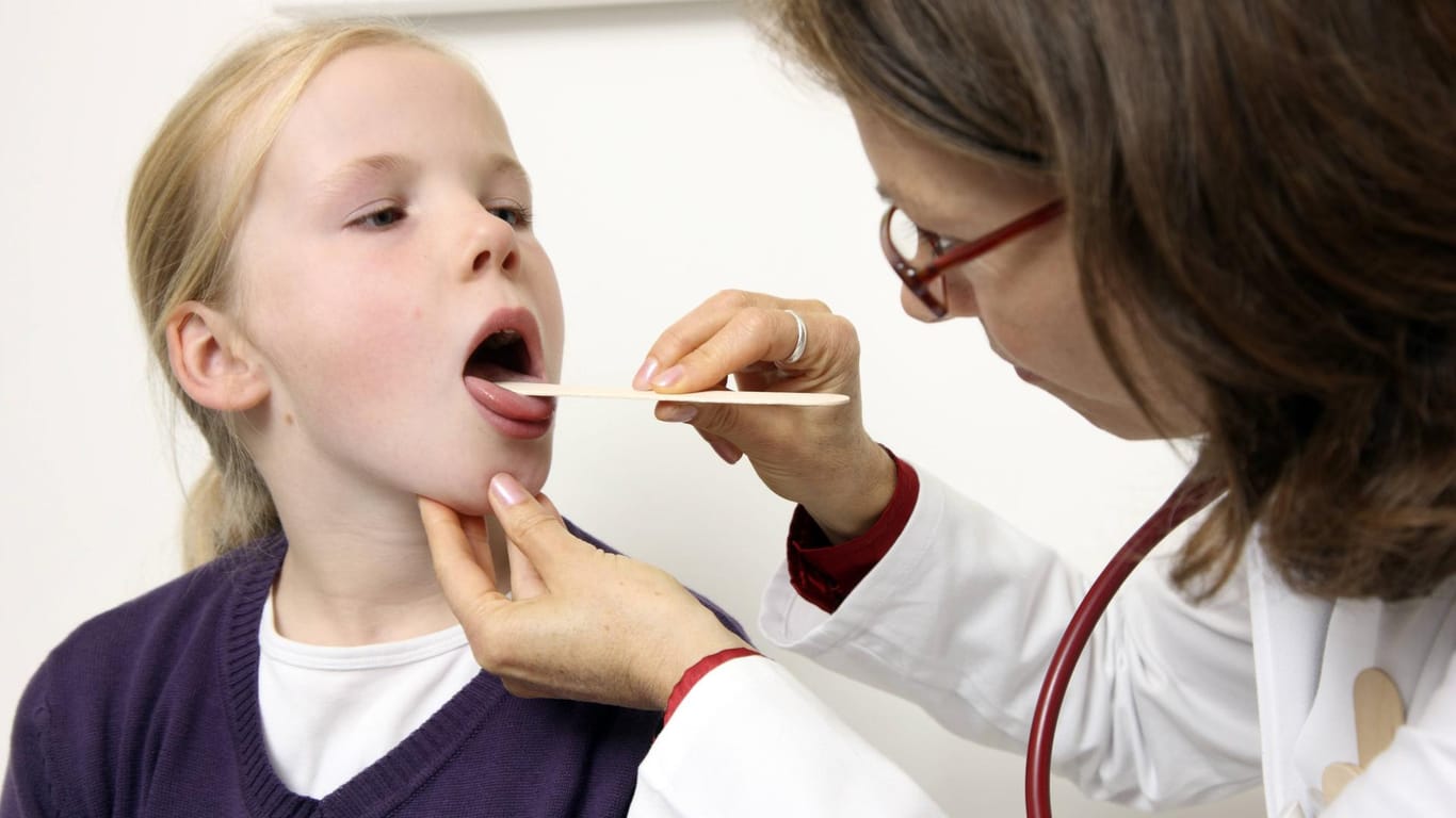 Eine Ärztin untersucht ein Mädchen: Wenn Kinder Halsschmerzen haben, sind häufig Streptokokken die Ursache.