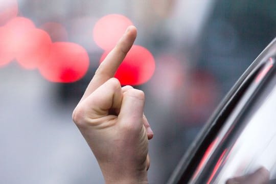 Einen sogenannten "Stinkefinger" zeigt ein Autofahrer.