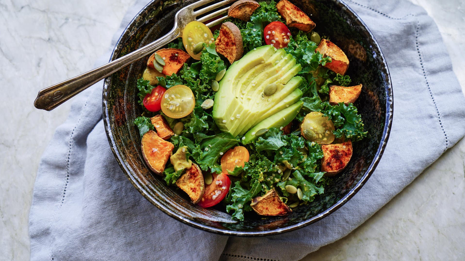 Grünkohl-Tomate-Süßkartoffel-Avocado-Salat: Die Ernährung soll der Mix aus möglichst unverarbeiteten Lebensmitteln, den Verzicht auf raffinierten Kohlenhydrate und viel frischem Gemüse sein.