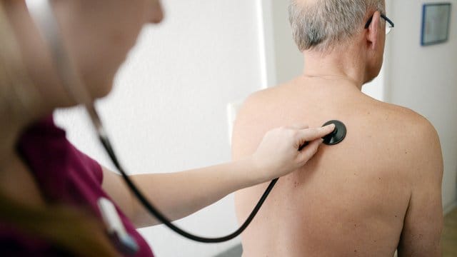 Eine Medizinerin untersucht einen Patienten.