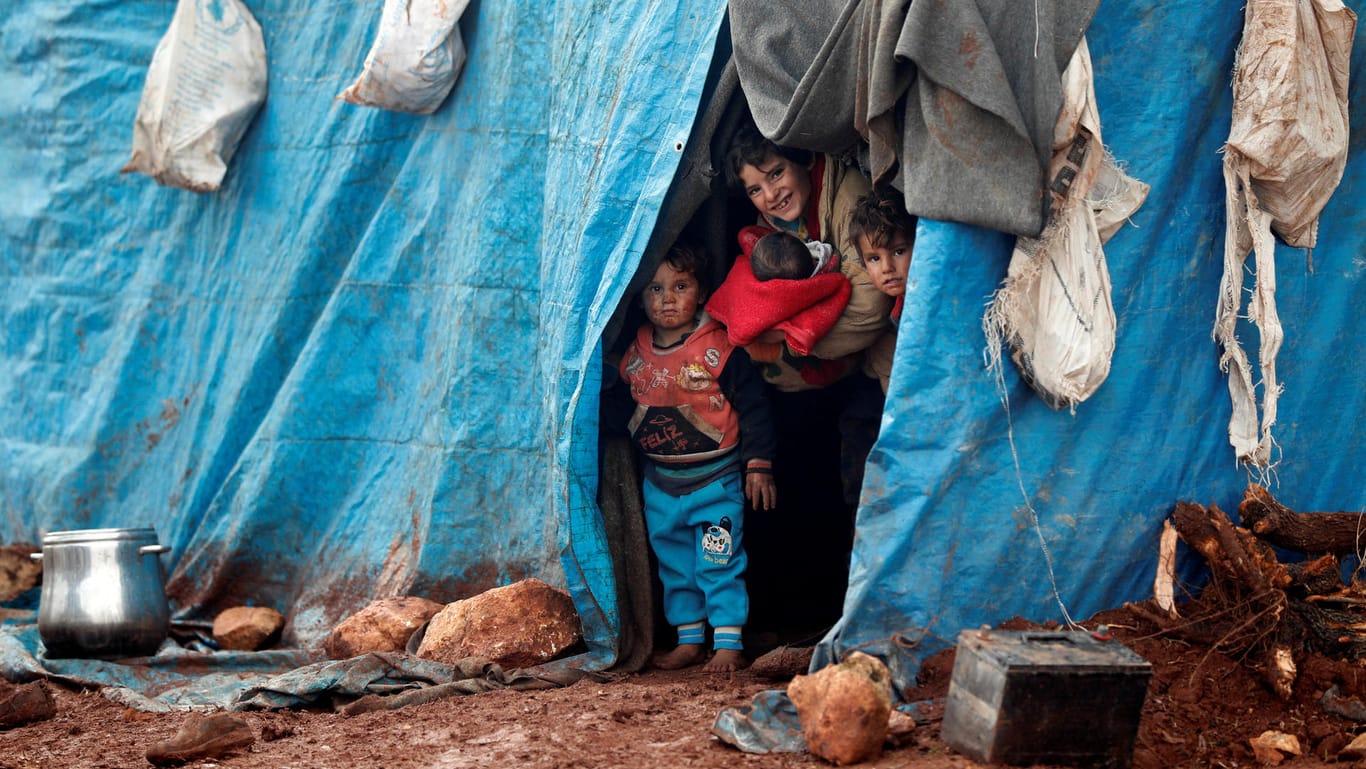 Kinder schauen aus einem Zelt in einem Flüchtlingscamp in Idlib nahe der syrisch-türkischen Grenze: Da die Situation in Syrien für Kinder zu gefährlich ist, genehmigen einige Behörden ihren Nachzug nach Deutschland - im Kreis Pinneberg durften auch die Mütter folgen.