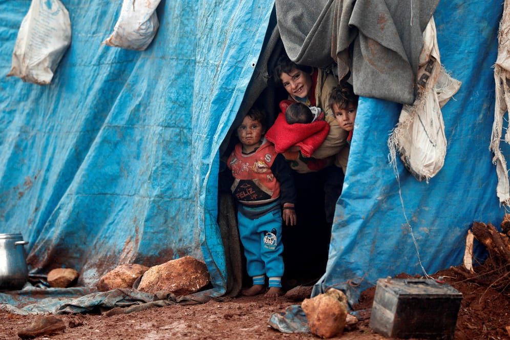 Kinder schauen aus einem Zelt in einem Flüchtlingscamp in Idlib nahe der syrisch-türkischen Grenze: Da die Situation in Syrien für Kinder zu gefährlich ist, genehmigen einige Behörden ihren Nachzug nach Deutschland - im Kreis Pinneberg durften auch die Mütter folgen.