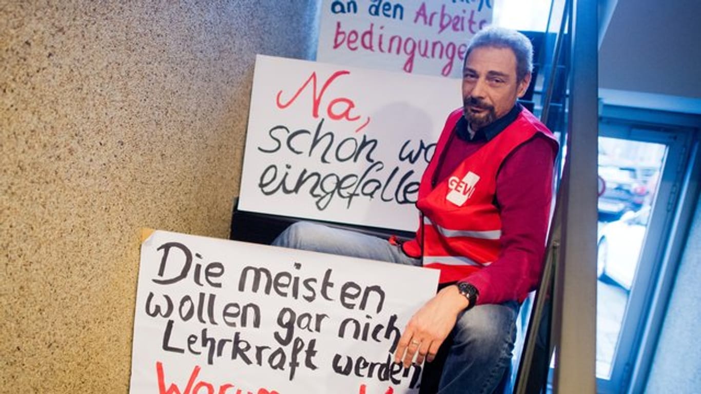 Gewerkschafter protestieren mit Plakaten am Rande einer Pressekonferenz der Gewerkschaft Erziehung und Wissenschaft (GEW).