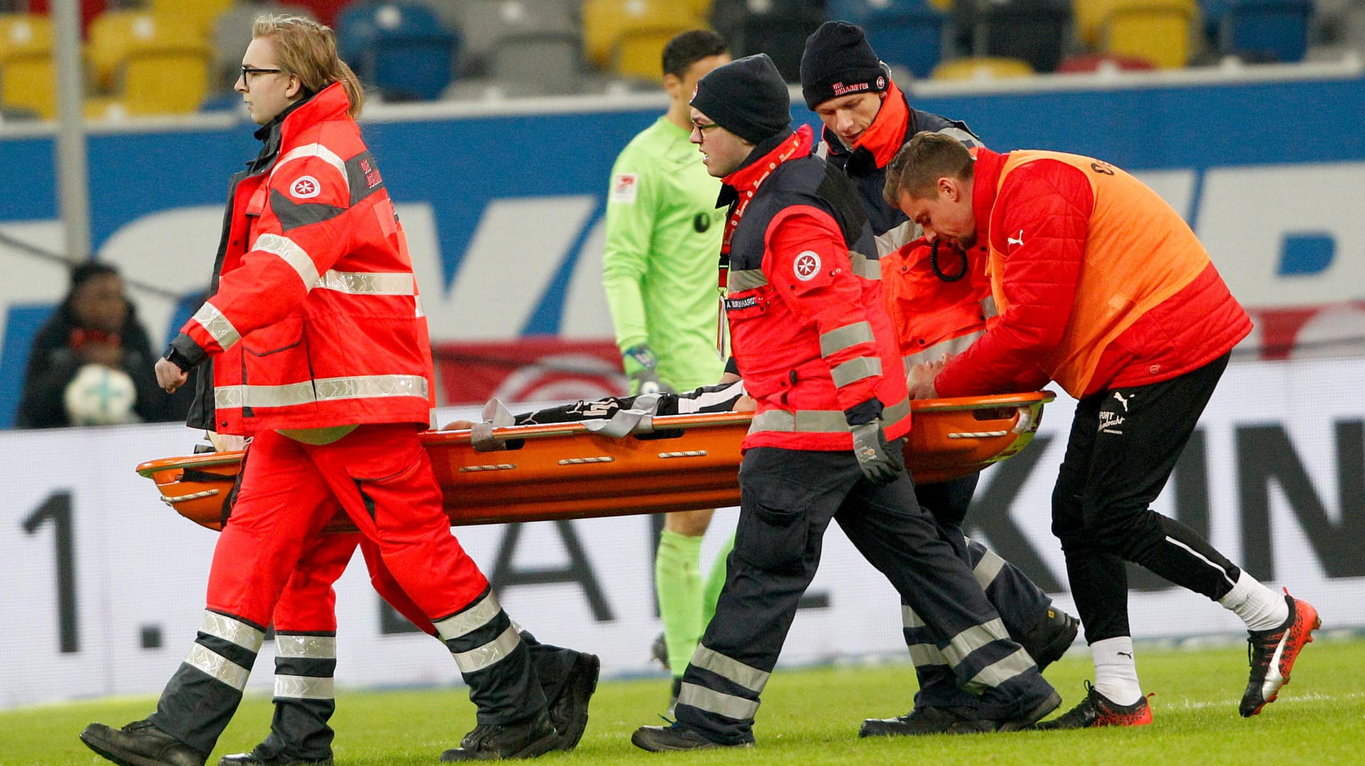Klingmann wird von Sanitätern auf einer Trage vom Platz gebracht.