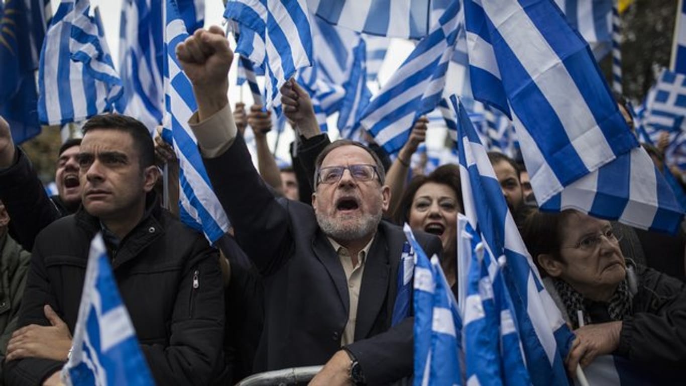 Demonstranten versammeln sich vor dem griechischen Parlament, halten Fahnen und Plakate hoch und rufen dabei Parolen.
