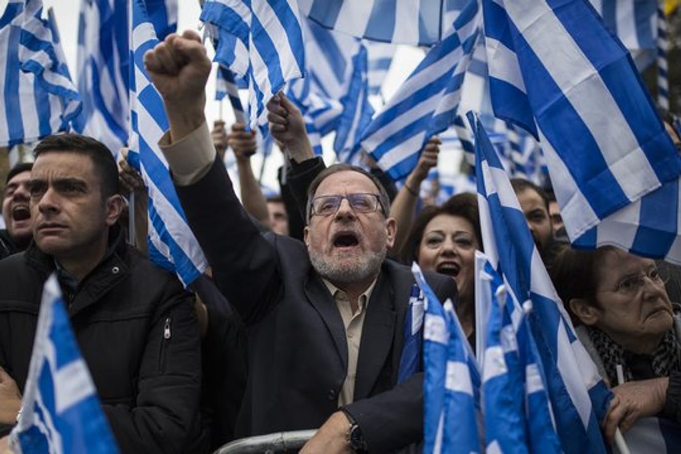 Demonstranten versammeln sich vor dem griechischen Parlament, halten Fahnen und Plakate hoch und rufen dabei Parolen.