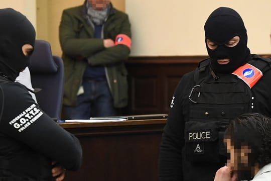 Der mutmaßliche islamistische Terrorist Salah Abdeslam sitzt am ersten Tag des Prozesses vor Polizisten im Gerichtssaal.