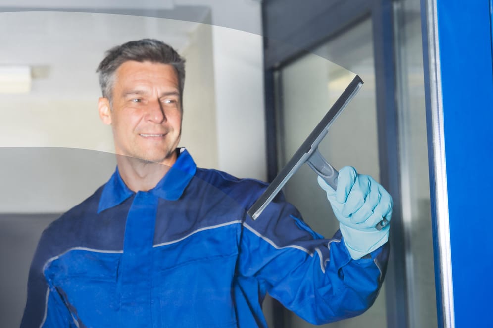 Männliche Putzkraft reinigt Fenster