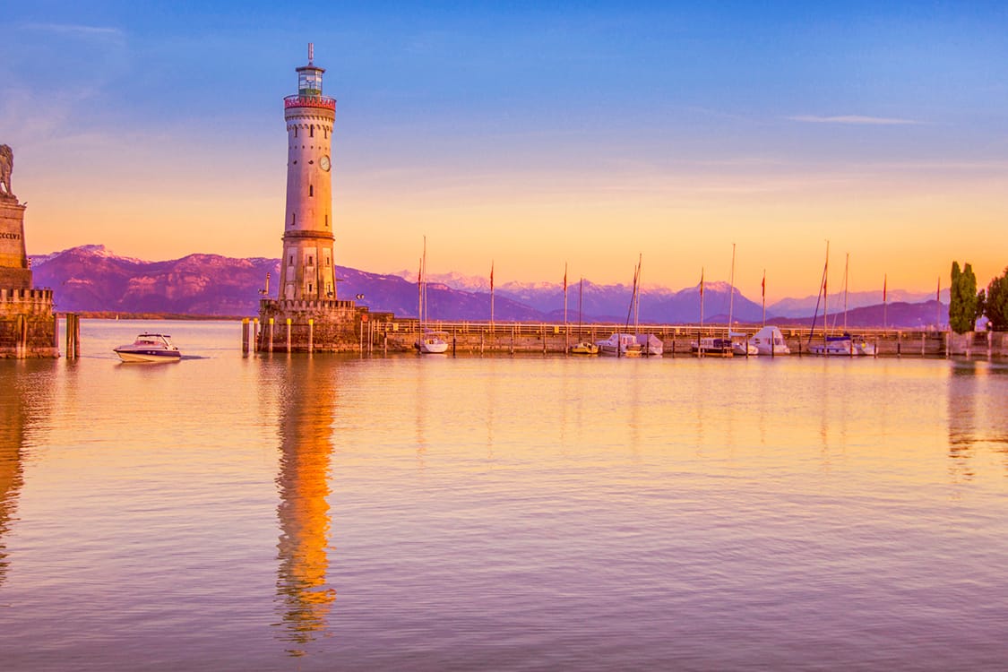 Der Hafen von Lindau: Urlauber der Bodensee-Insel genießen milde Temperaturen vor der Kulisse schneebedeckter Berggipfel.