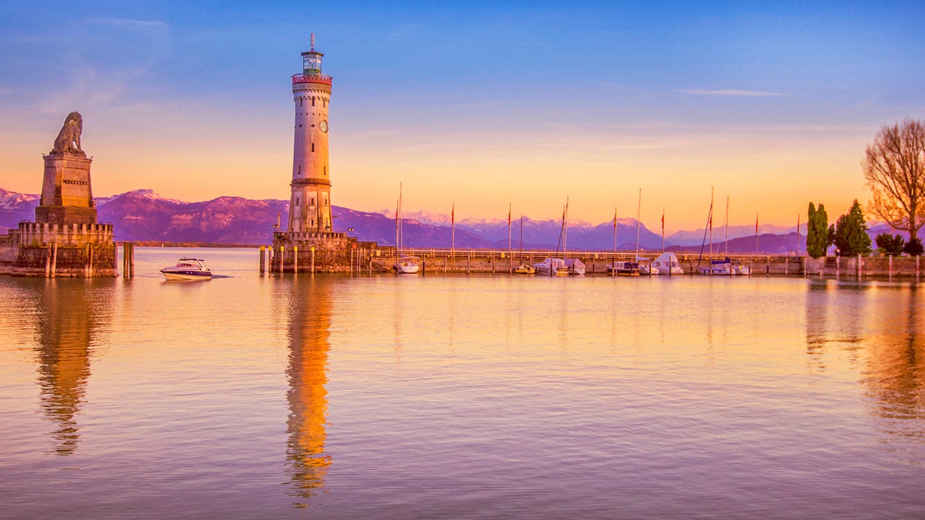 Der Hafen von Lindau: Urlauber der Bodensee-Insel genießen milde Temperaturen vor der Kulisse schneebedeckter Berggipfel.