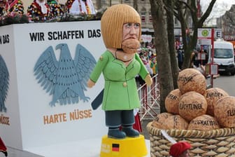 Karnevalisten ziehen am Rosenmontag mit einem Motivwagen durch Köln.