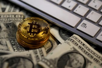 Physische Bitcoin-Münzen liegen auf Dollar-Noten