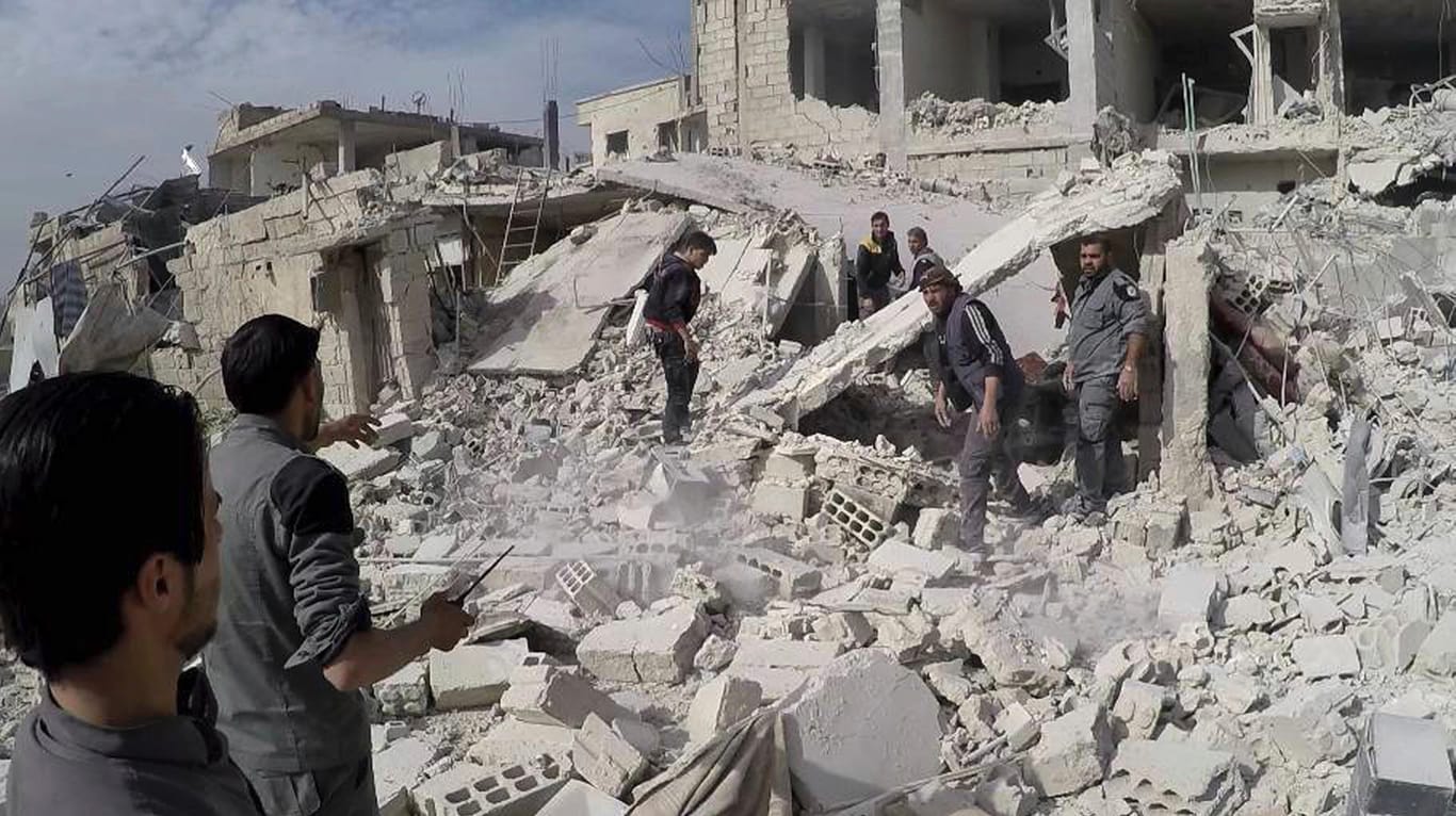 Zivilschutzarbeiter und Zivilisten bei einem zerstörten Gebäudes in dem Rebellengebiet Ghuta: Damaskus wirft USA Kriegsverbrechen vor.