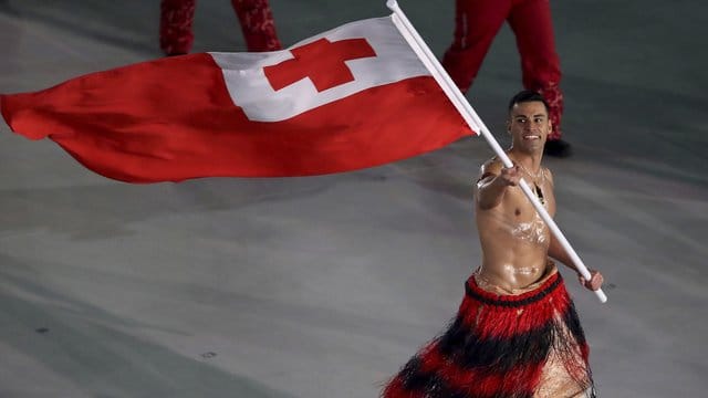 Skilangläufer Pita Taufatofua aus Tonga trägt die Flagge seines Landes mit bloßem Oberkörper. Skilangläufer Pita Taufatofua aus Tonga trägt die Flagge seines Landes mit bloßem Oberkörper.