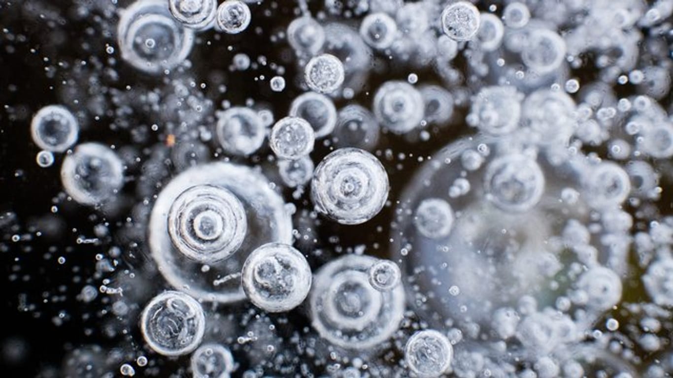 Luftblasen sind im Eis einer zugefrorenen Wasserfläche zu sehen.