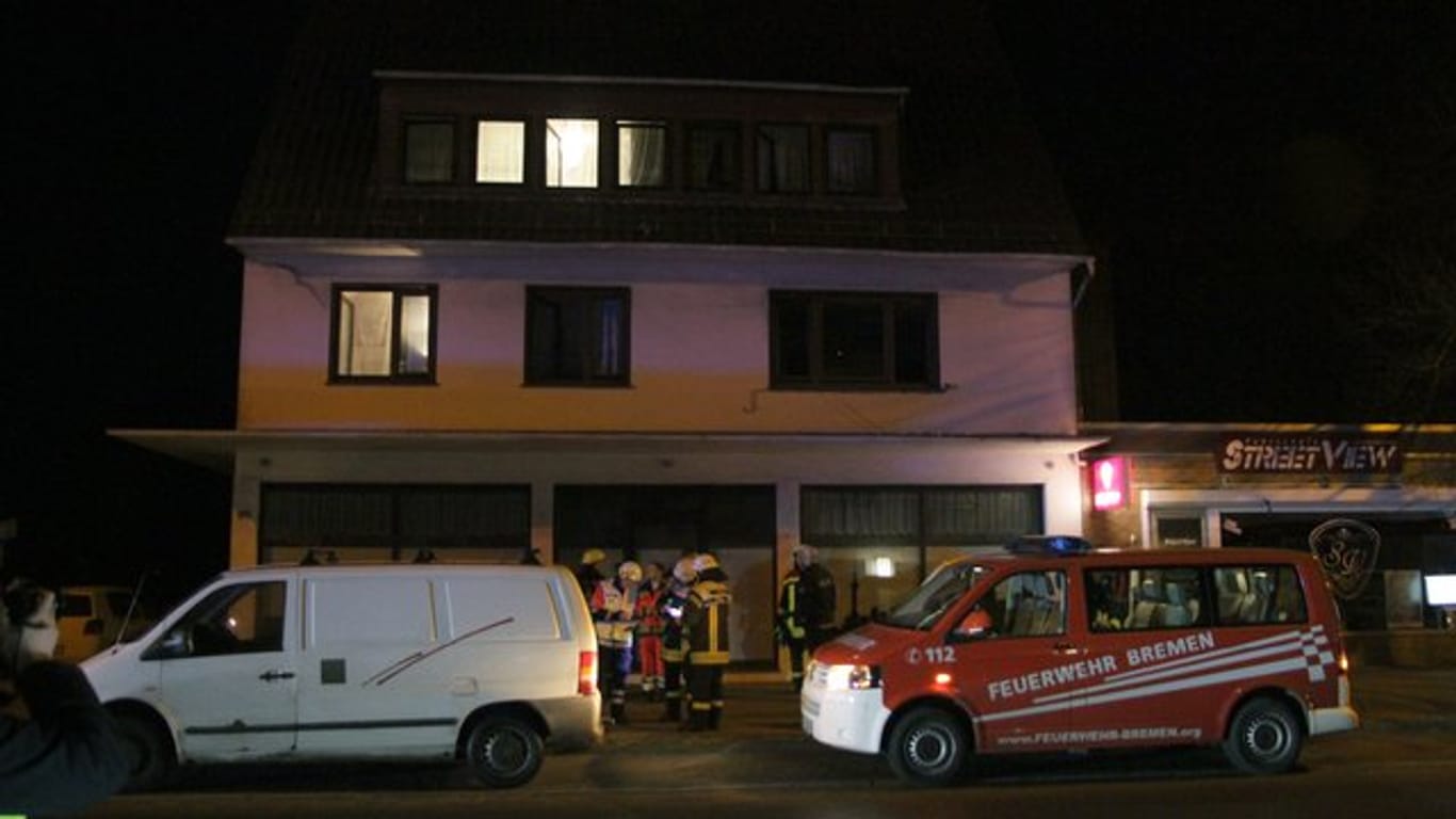 Einsatzkräfte des Rettungsdienstes und der Feuerwehr stehen am frühen Morgen vor dem Haus in Bremen-Farge, in dem bei einem Grillabend im Keller acht Menschen teils lebensgefährlich verletzt wurden.
