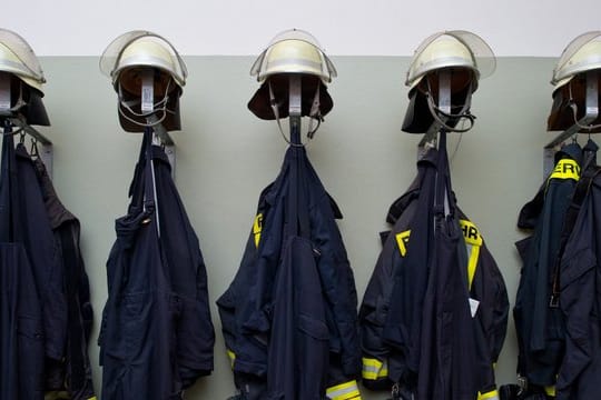 Feuerwehruniformen hängen in einem Gebäude einer Freiwilligen Feuerwehr (Symbolfoto): Gegen mehrere Feuerwehrleute wird wegen eines Hackerangriffs ermittelt.