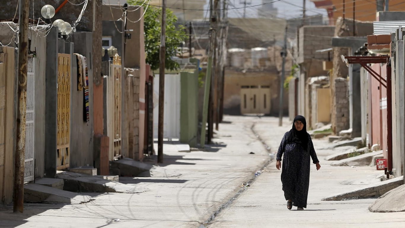 A woman walks in an empty street in Tuz Khurmato