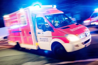 Ein Rettungswagen der Feuerwehr fährt mit Blaulicht durch eine Straße: Bei einem Unfall in Mönchengladbach ist der Fahrer eines Motorrollers ums Leben gekommen, seine Beifahrerin wurde schwer verletzt. (Archivbild)