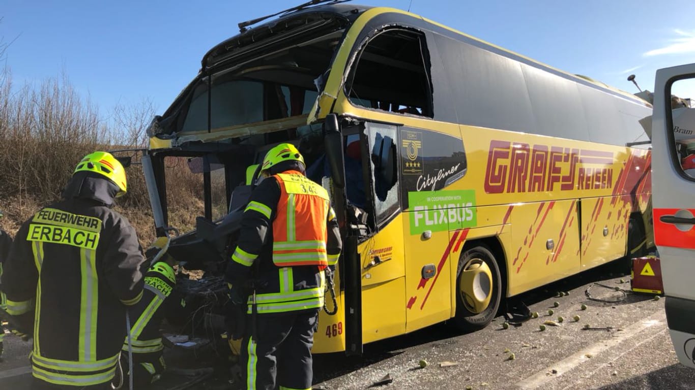 Unfall auf der A3: Einsatzkräfte der Feuerwehr stehen neben der schwer beschädigten Front des Reisebusses.