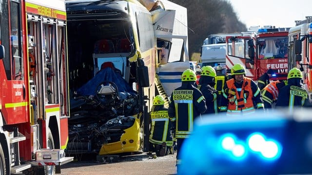 Nach dem Unfall zwischen einem Reisebus und zwei LKW stehen Helfer an der Unfallstelle.