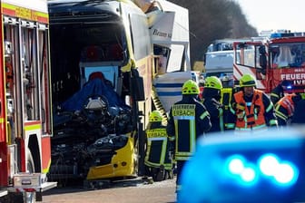 Nach dem Unfall zwischen einem Reisebus und zwei LKW stehen Helfer an der Unfallstelle.