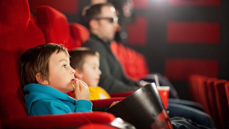 Ein Vater mit zwei Jungen im Kino: Im Vorschulalter sind Kinder mit dem Geschehen auf der Leinwand meist noch überfordert.