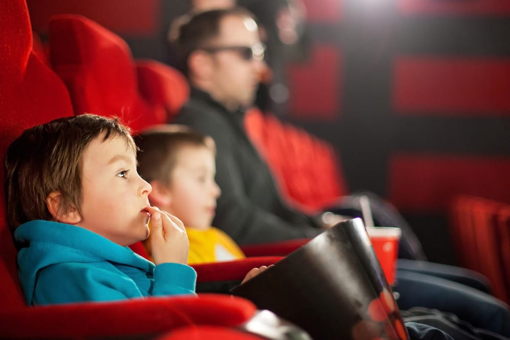 Ein Vater mit zwei Jungen im Kino: Im Vorschulalter sind Kinder mit dem Geschehen auf der Leinwand meist noch überfordert.