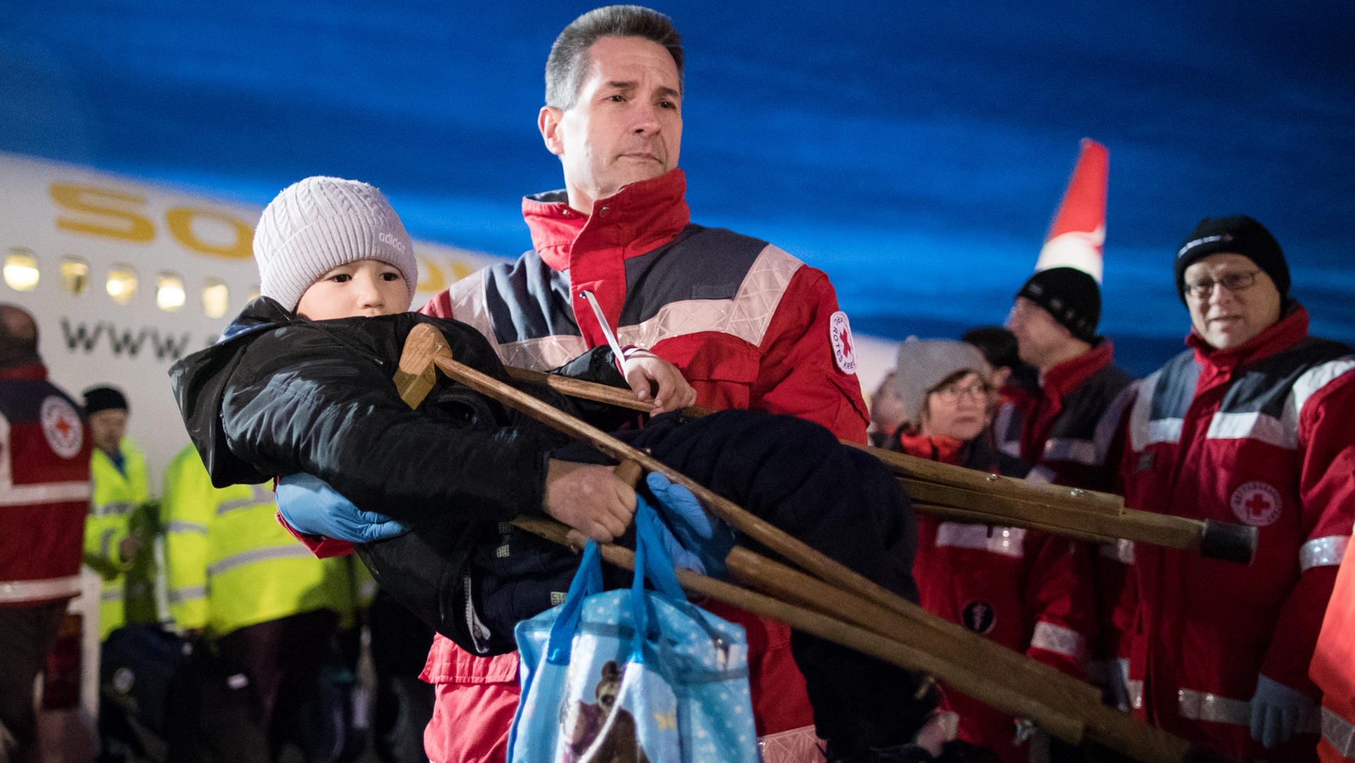 Ein kleiner schwerkranker Junge auf den Armen eines Mitarbeiters des Deutschen Roten Kreuzes: Mehr als 120 schwerkranke Kinder sind mit einer Hilfsorganisation zur Behandlung nach Deutschland gebracht worden.