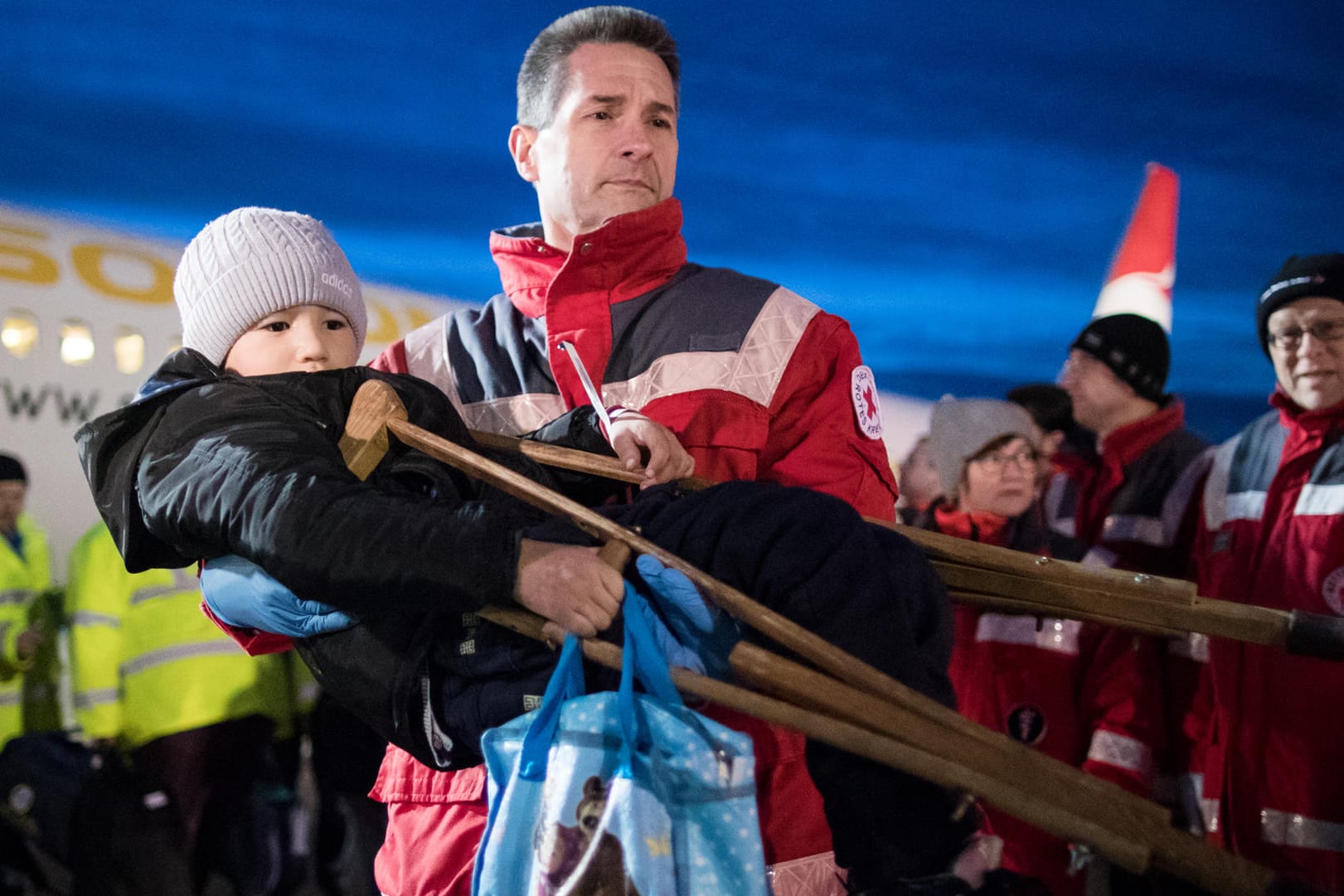 Ein kleiner schwerkranker Junge auf den Armen eines Mitarbeiters des Deutschen Roten Kreuzes: Mehr als 120 schwerkranke Kinder sind mit einer Hilfsorganisation zur Behandlung nach Deutschland gebracht worden.