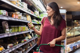 Frau beim Einkaufen: Lebensmittelverpackungen beinhalten oft Warnhinweise, wo die Bedeutung oder die Wahrheit rätselhaft ist.