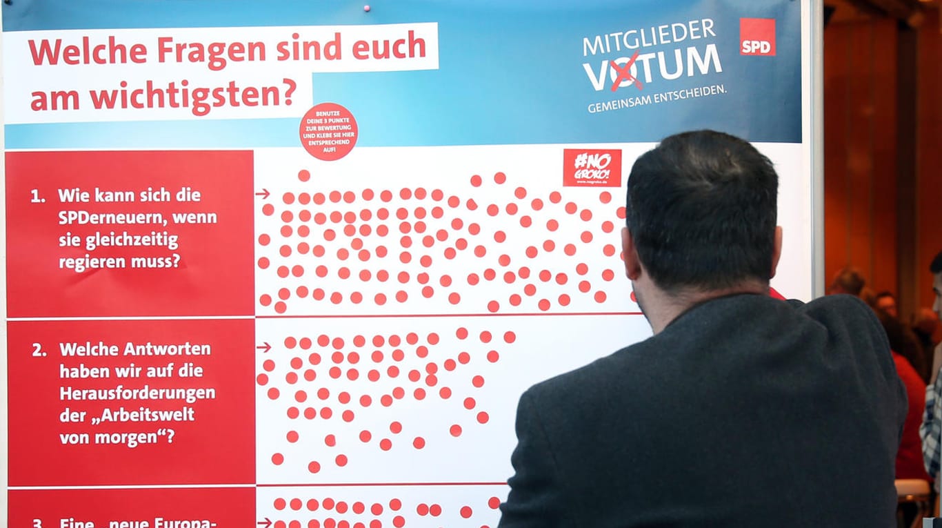 Ein SPD-Mitglied klebt einen Aufkleber auf eine Tafel, die Schwerpunktthemen der Sozialdemokraten verdeutlicht: Die Abstimmung der SPD-Mitglieder über die Groko hat begonnen.