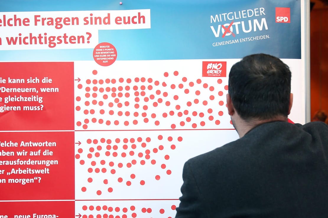 Ein SPD-Mitglied klebt einen Aufkleber auf eine Tafel, die Schwerpunktthemen der Sozialdemokraten verdeutlicht: Die Abstimmung der SPD-Mitglieder über die Groko hat begonnen.