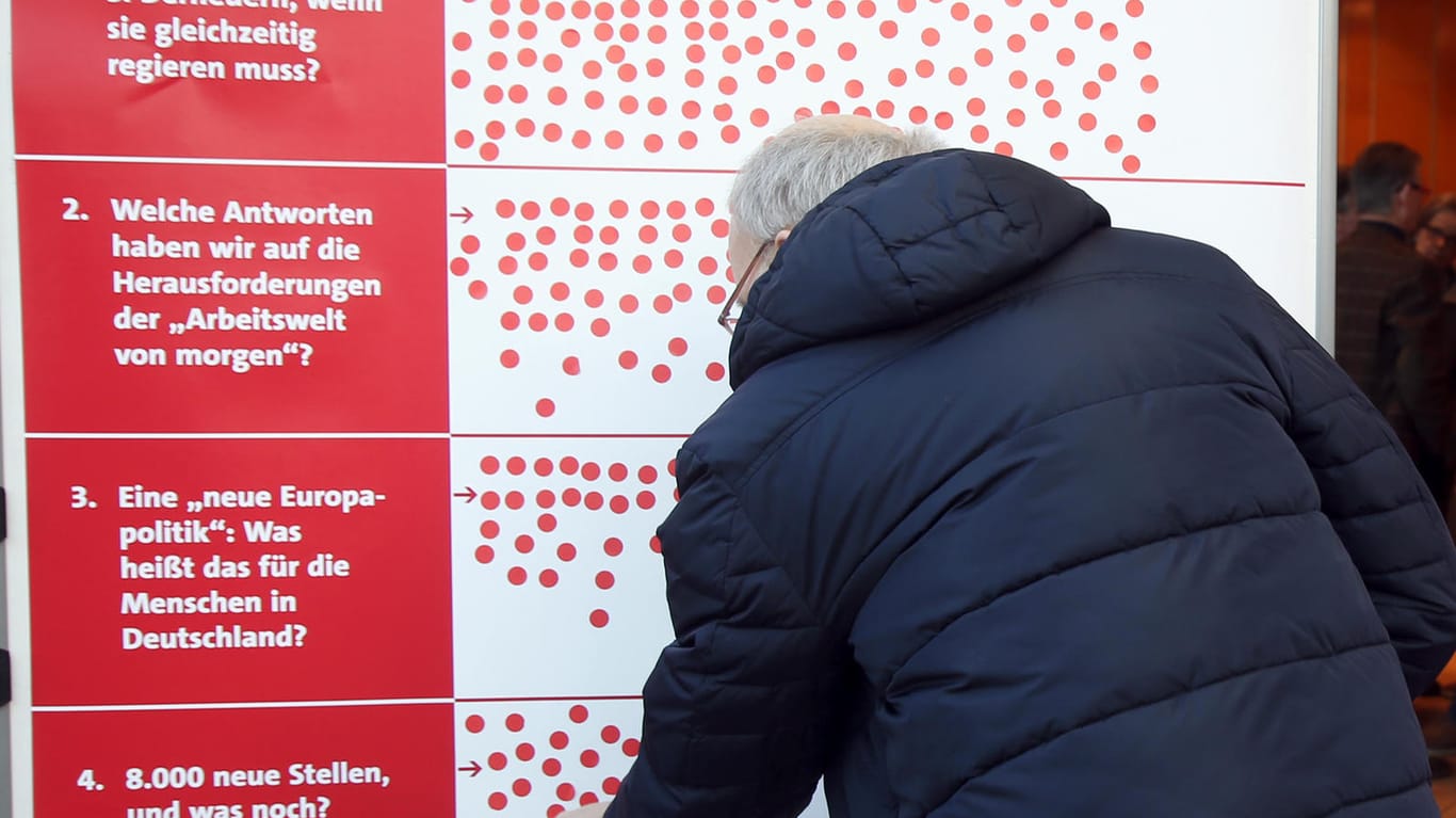 SPD-Regionalkonferenz in Kamen, NRW: Ein Genosse klebt einen Aufkleber auf eine Tafel mit Schwerpunktthemen.