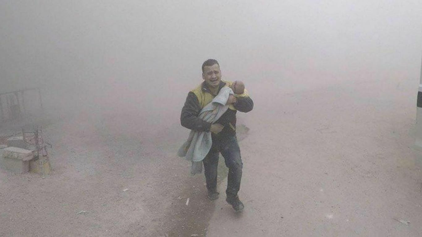 Ein Vater trägt sein Baby durch die Trümmer im Rebellengebiet Ost-Ghuta: Das Foto haben die Weißen Helme verbreitet.