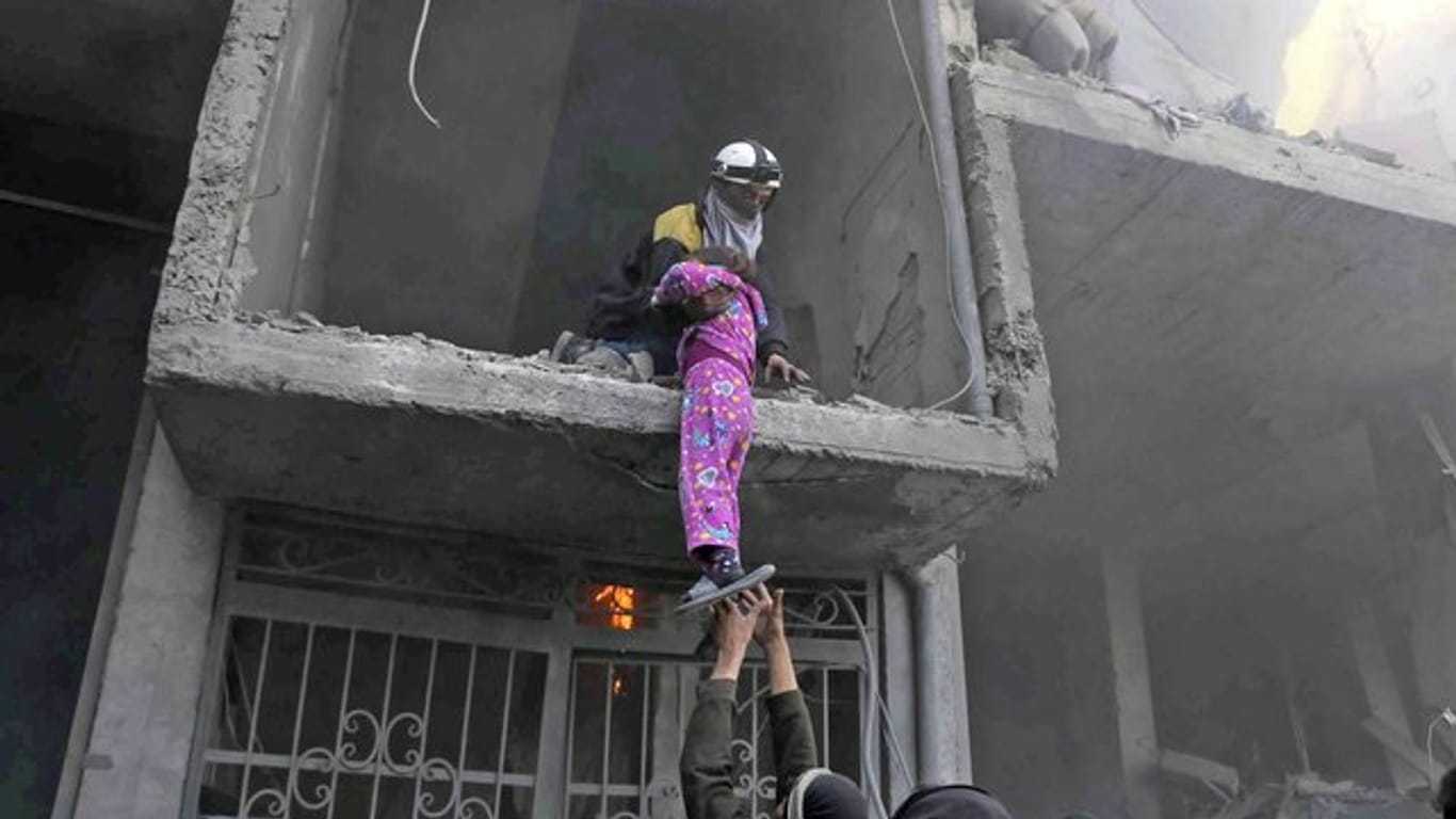 Mitglieder des Syrischen Zivilschutzes retten während eines Luftangriffs ein Mädchen aus einem zerstörten Gebäude in Ost-Ghuta.