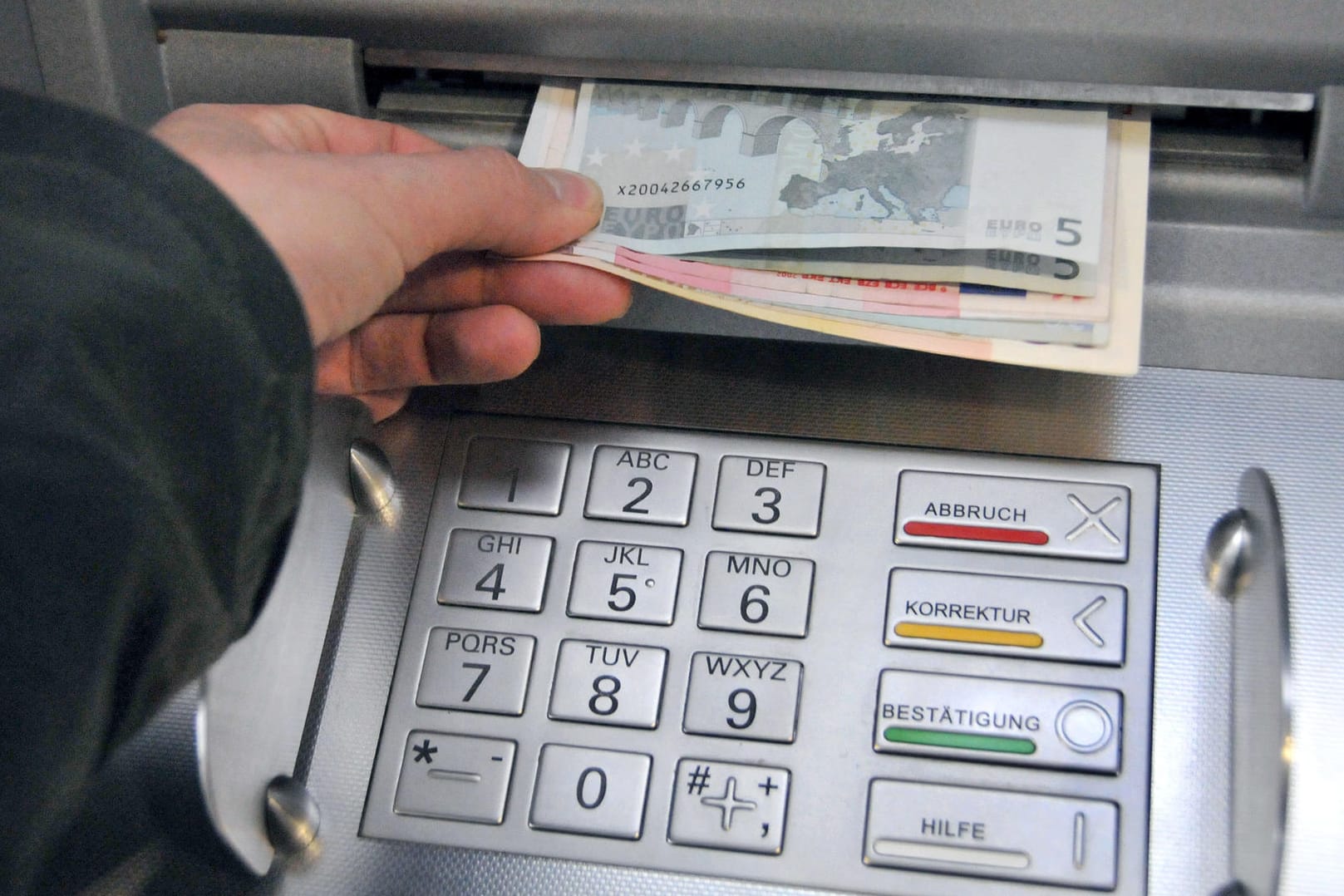 Eine Hand entnimmt dem Geldschlitz eines Bankautomaten die gewünschten Banknoten: Die Spur zu der vermissten 14-Jährigen und ihrem Betreuer führt nach Hamburg. Eine der beiden Personen soll hier versucht haben, Geld abzuheben. (Symbolbild)