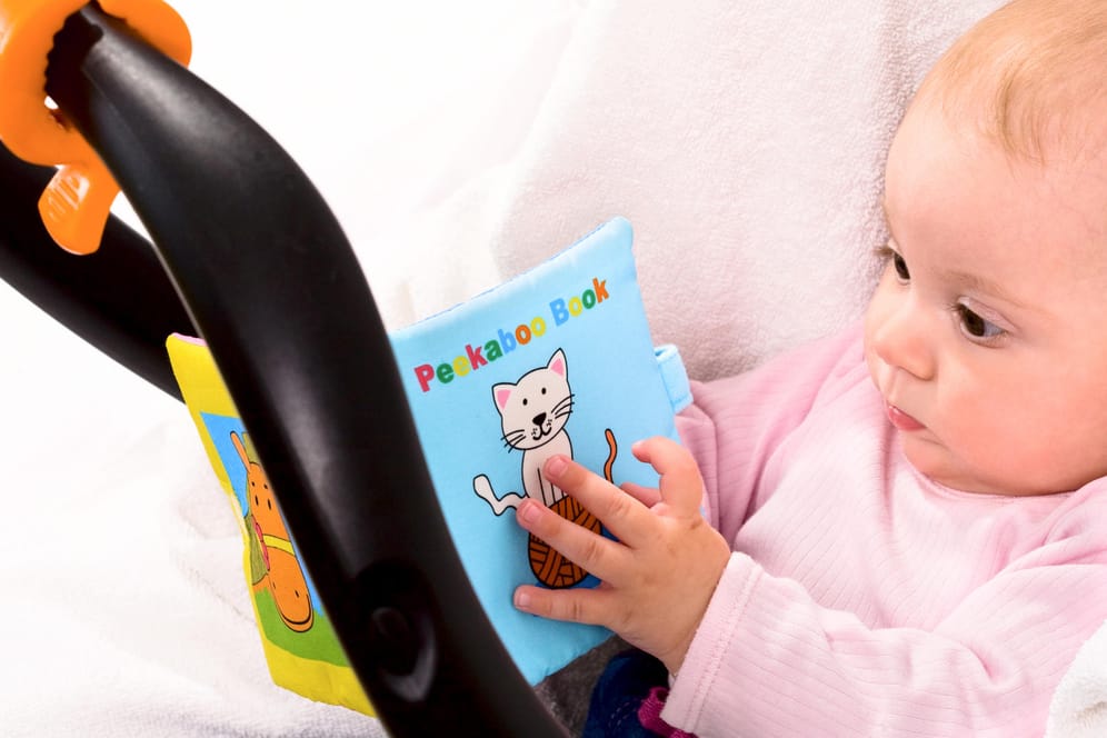 Baby mit Stoffbilderbuch: Im Test bestanden viele Stoffbilderbücher die Prüfung nach der Spielzeugnorm nicht. (Symbolbild)