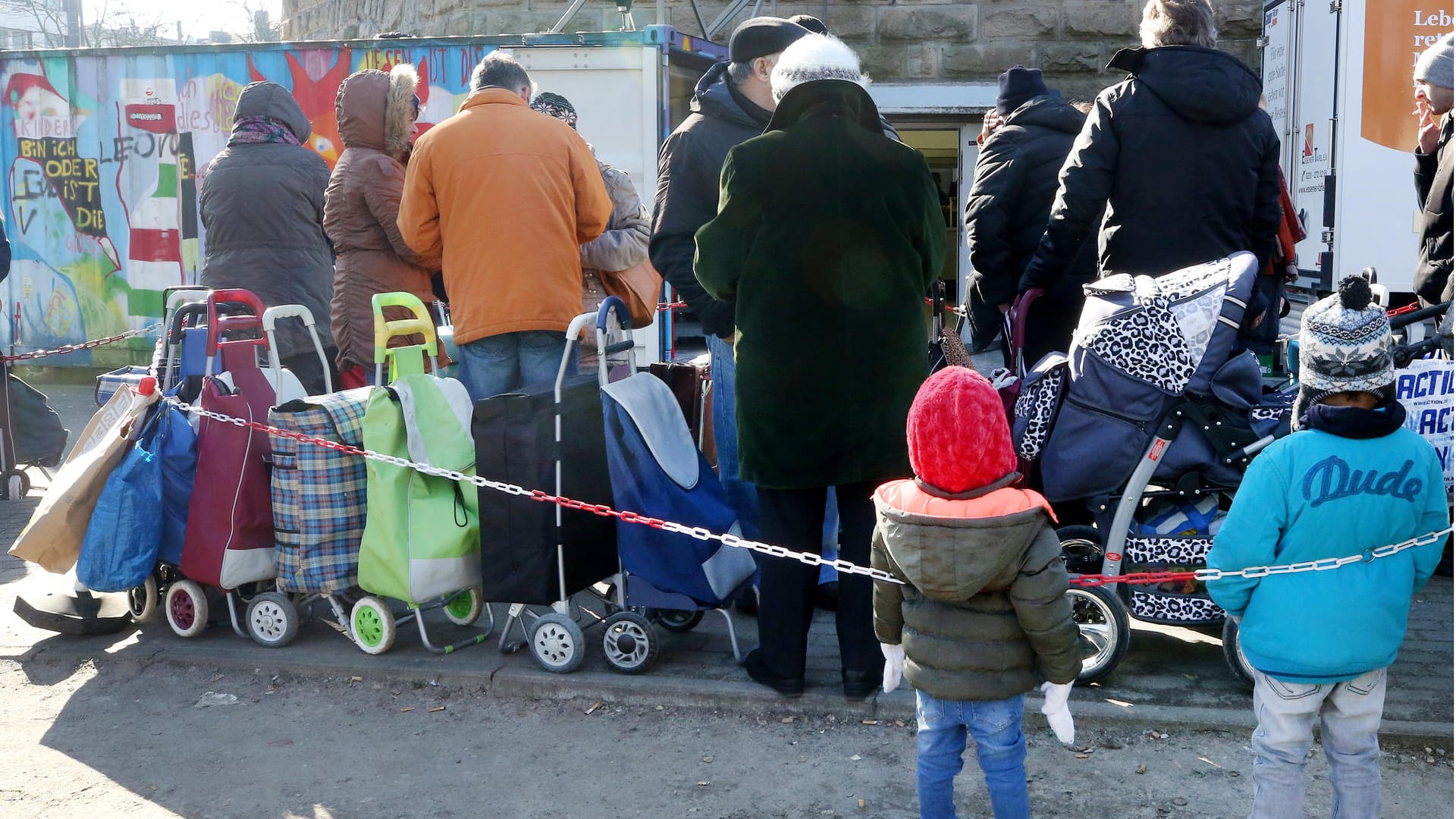 Helfer im Blickpunkt: An einer Ausgabestelle der Essener Tafel stehen Bedürftige mit ihren Einkaufstrolleys Schlange