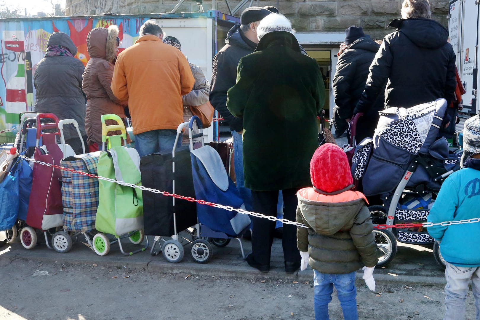 Helfer im Blickpunkt: An einer Ausgabestelle der Essener Tafel stehen Bedürftige mit ihren Einkaufstrolleys Schlange