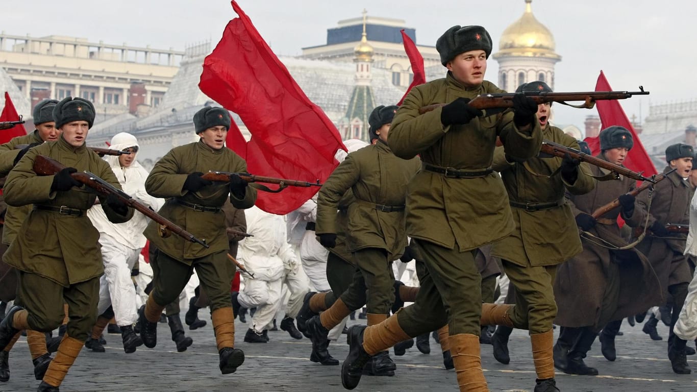 Russische Soladten spielen bei einer Parade Soldaten der Roten Armee im Zweiten Weltkrieg.