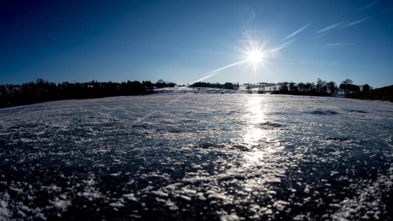 Die Sonne scheint über einem mit Eis bedeckten Teich im Harz in Niedersachsen.