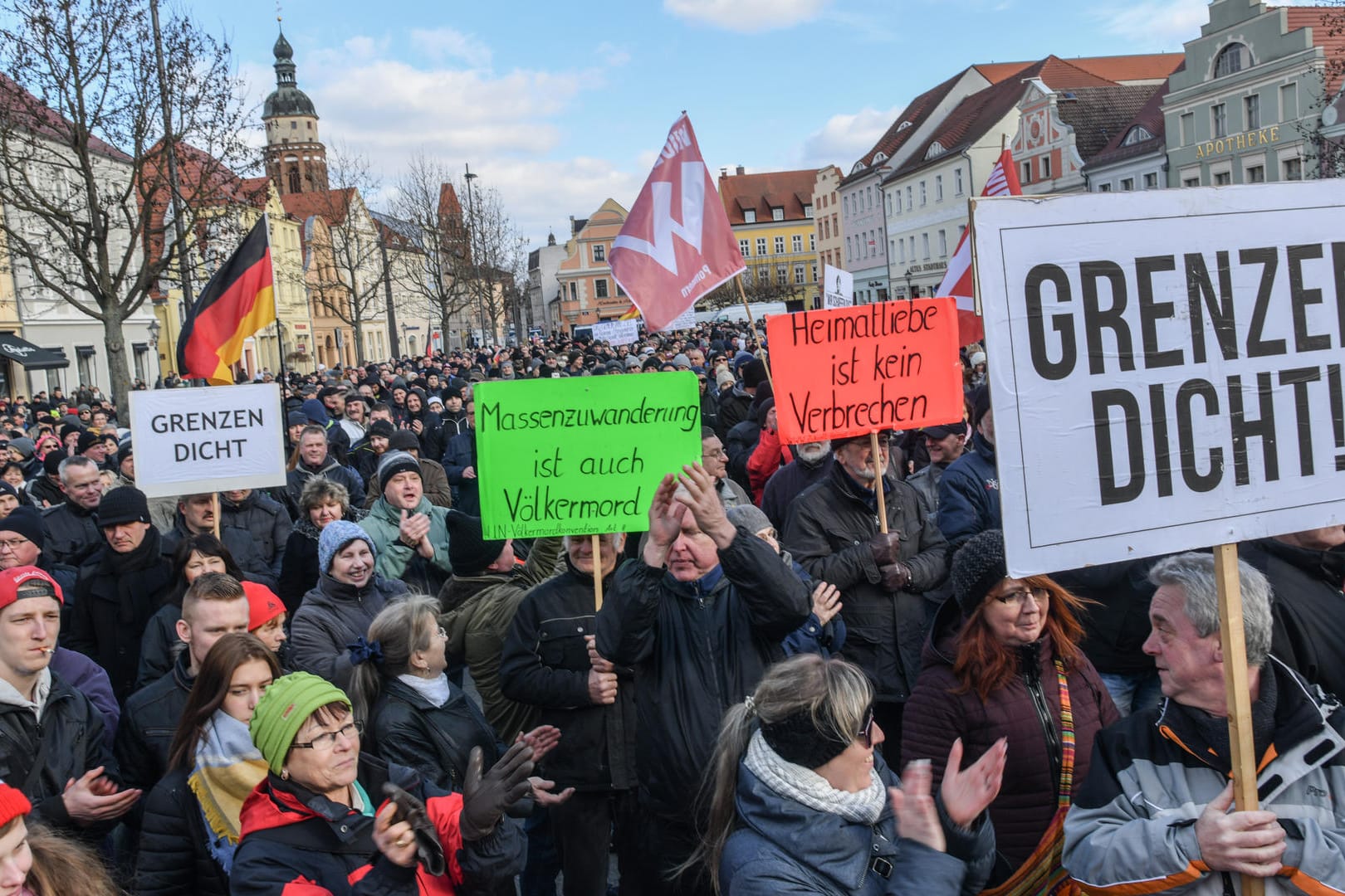 Cottbus: Demonstranten stehen auf dem Altmarkt mit Fahnen und Plakaten und protestieren gegen Zuwanderung und die Asyl-Politik der Bundesregierung.