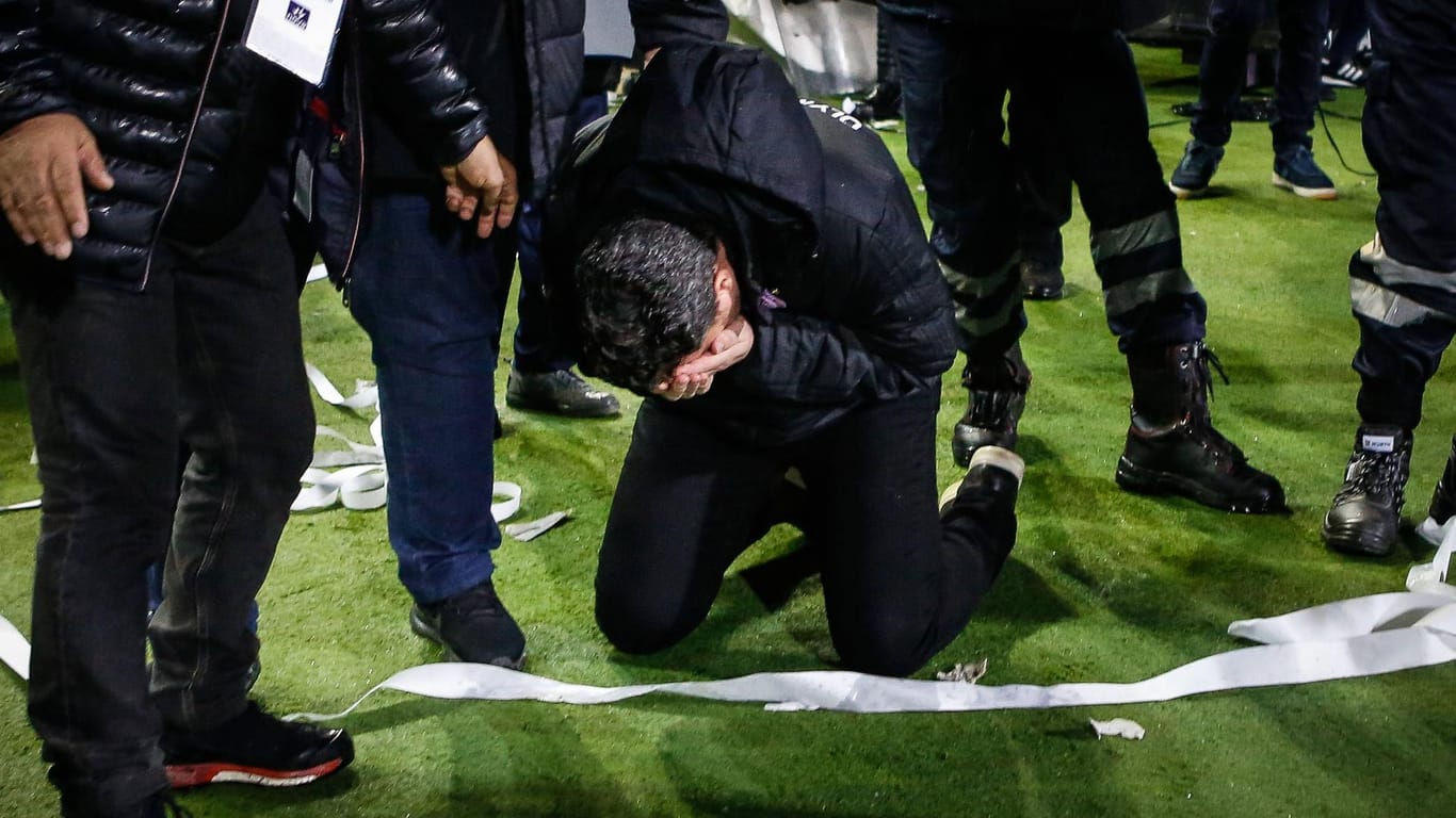 Oscar Garcia geht zu Boden: Der Trainer von Olympiakos Piräus wurde von einem Gegenstand am Kopf getroffen.