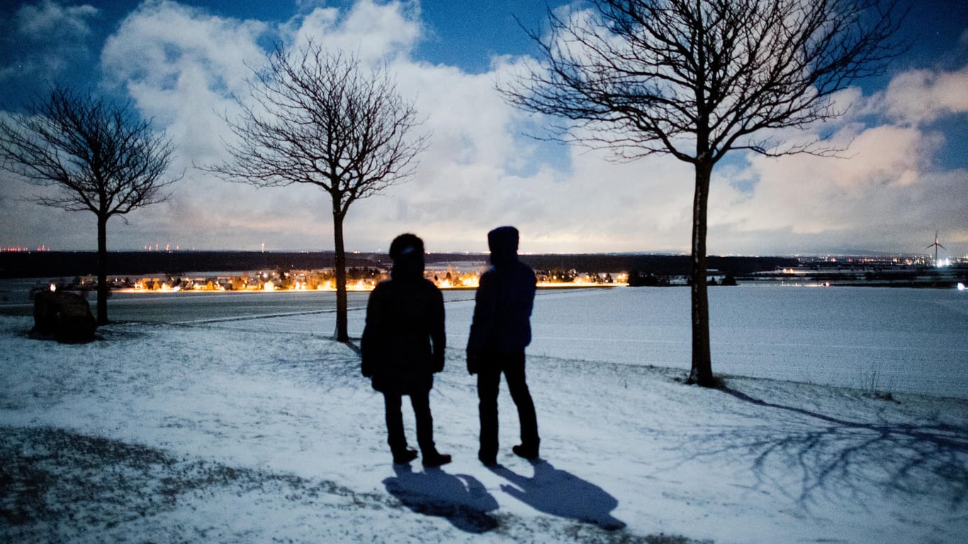 Zwei Spaziergänger stehen in einer eiskalten Winternacht im Mondschein auf dem Kronsberg: In Deutschland kam es durch Hoch "Hartmut" zu der kältesten Nacht des Jahres.