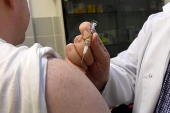 Jens Ohlendorf (r), Facharzt für Allgemeinmedizin, setzt in seiner Praxis in Langenhagen (Niedersachsen) einem Patienten eine Grippeschutzimpfung.