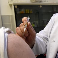 Jens Ohlendorf (r), Facharzt für Allgemeinmedizin, setzt in seiner Praxis in Langenhagen (Niedersachsen) einem Patienten eine Grippeschutzimpfung.