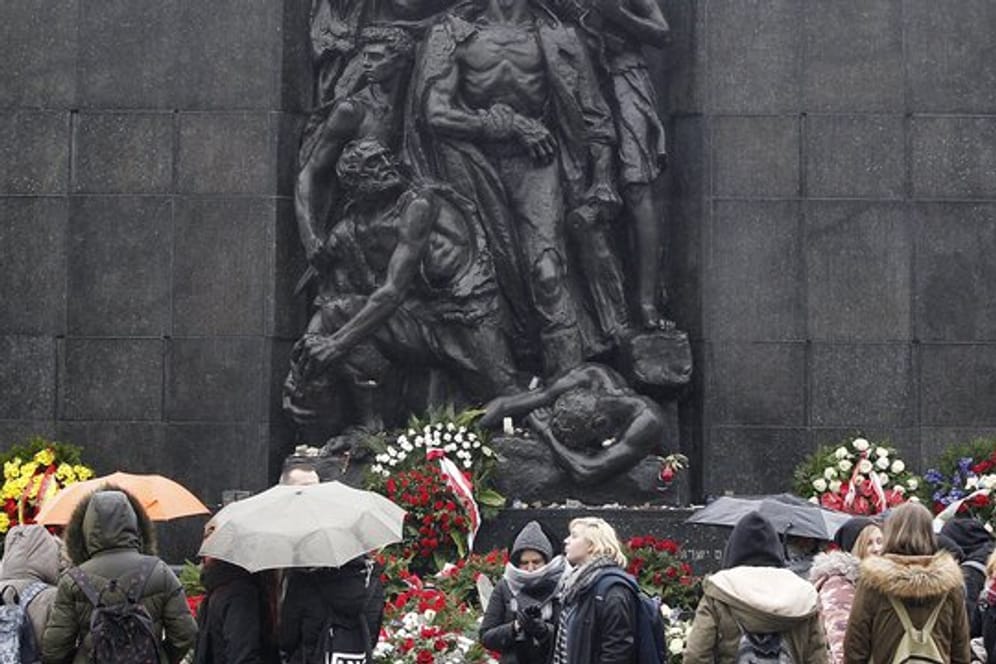 Besucher stehen vor dem Denkmal des Warschauer Aufstandes.